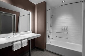 Un baño moderno con un espejo grande, lavamanos blanco y ducha a pie.