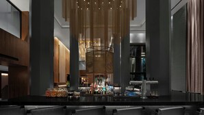 A modern bar area with a long counter, several chairs, and a decorative hanging light fixture.