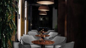 A modern interior with wicker chairs, round wooden tables, and pendant lighting.