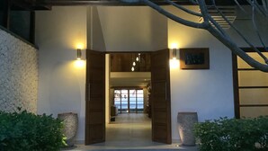 Une entrée moderne avec une porte en bois, deux lampes fixées au mur et une vue sur l’intérieur.