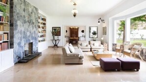 A spacious living room with a fireplace, a large bookshelf, and a view of the outdoors. - CORONEL - CASERÍO DE GUAZA (Palm-Mar)