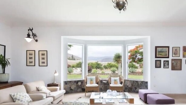 A living room with a sofa, armchairs, a coffee table, and a view of a garden through large windows. - CORONEL - CASERÍO DE GUAZA (Palm-Mar)