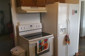 Una cocina con estufa, horno y refrigerador blancos.