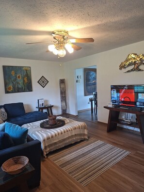 A living room with a ceiling fan, a sofa, a coffee table, a TV, and artwork on the walls. - Sunrise Escape; Come enjoy breath taking sunrises! (Spring City)
