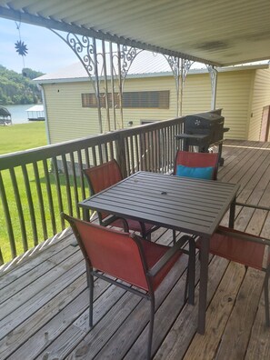 A covered outdoor deck with a table and chairs, a grill, and a view of a lake. - Sunrise Escape; Come enjoy breath taking sunrises! (Spring City)
