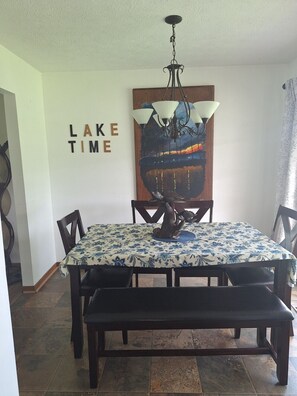 A dining area with a table set for four, a bench, a chandelier, and a wall with a painting and the words 'LAKE TIME'. - Sunrise Escape; Come enjoy breath taking sunrises! (Spring City)