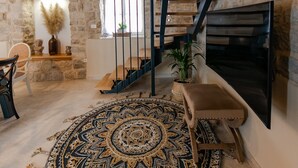 A spacious living area with a large round rug, a fireplace, and a stone wall. - Villa Bante - Luxury Stone House (Kastela)