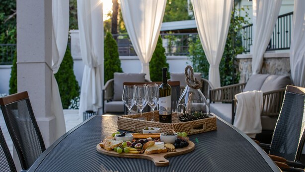 An outdoor dining area with a table set for a meal, surrounded by white curtains and greenery. - Villa Bante - Luxury Stone House (Kastela)
