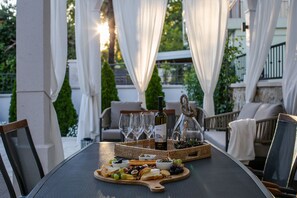 An outdoor dining area with a table set for a meal, surrounded by white curtains and greenery. - Villa Bante - Luxury Stone House (Kastela)