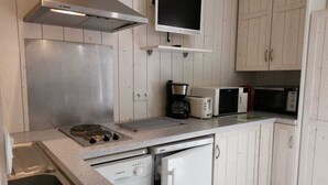 A compact kitchen with a Bosch range hood, a microwave, a toaster, and a coffee maker.