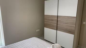 Un dormitorio con una cama, un armario blanco y una toalla en el suelo.