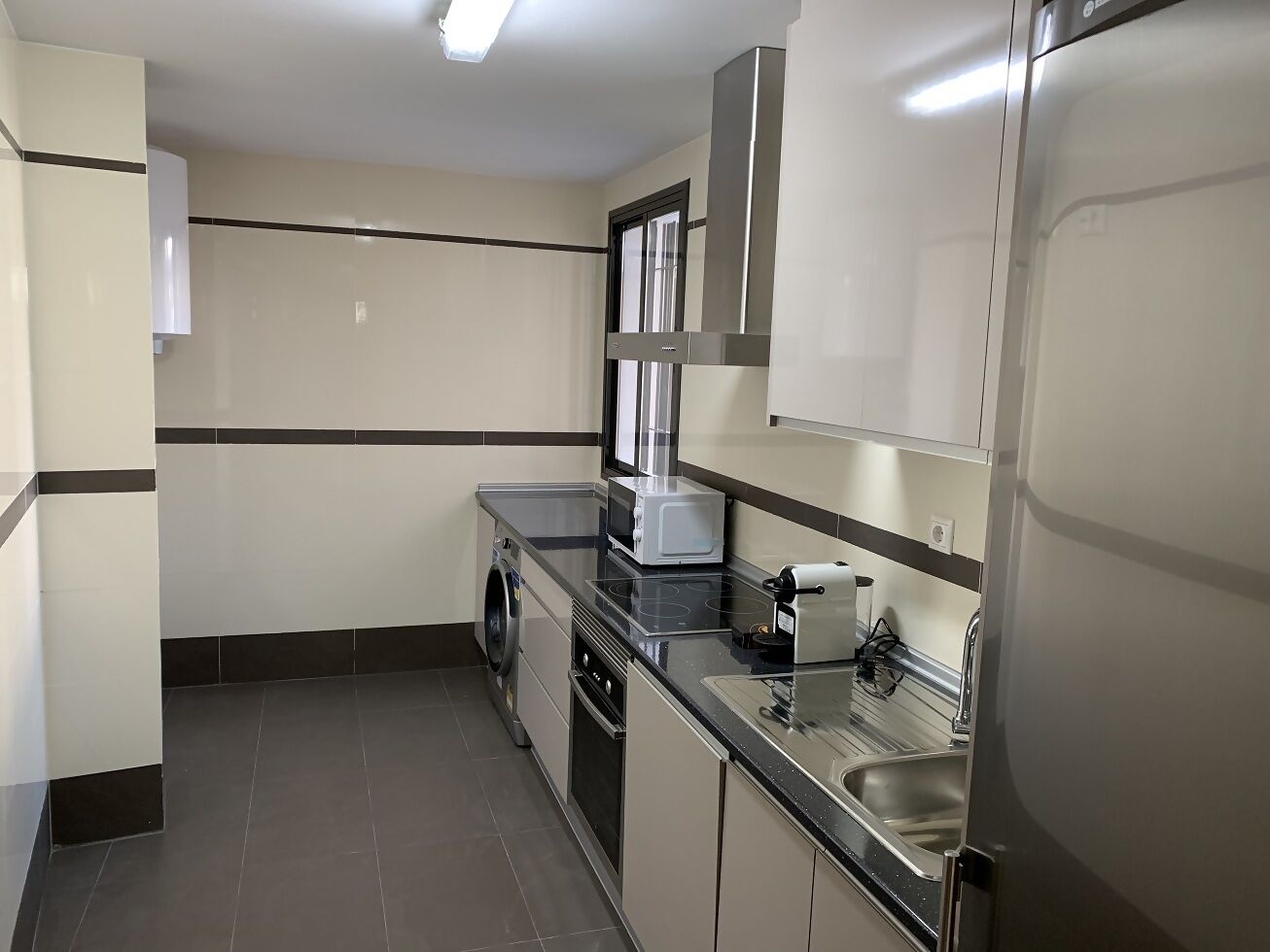Cocina compacta con lavadora, microondas y estufa.