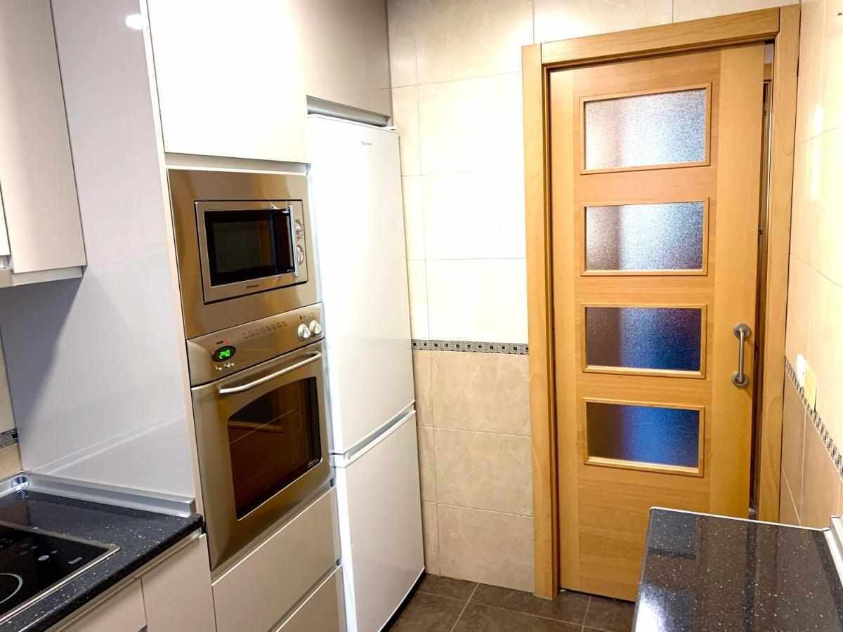 A kitchen with a microwave, oven, and refrigerator. There is a wooden door with frosted glass panels.