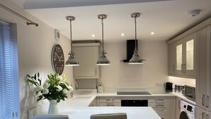 Una cocina moderna con una isla central, luces colgantes, electrodomésticos integrados y una lavadora.