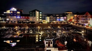 A marina with boats docked, surrounded by colorful buildings with illuminated windows. - Luxurious Exmouth marina apartment, a few minutes from miles of sandy beach (Exmouth)
