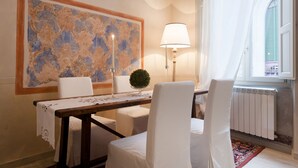 A dining area with a table set for two, a lamp, and a large abstract painting on the wall. - San Lorenzo Apartment (Firenze)