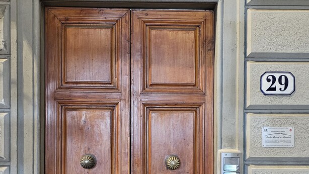 A wooden double door with a metal grille above it, a number '29' sign, and a keypad lock on the right side. - San Lorenzo Apartment (Firenze)