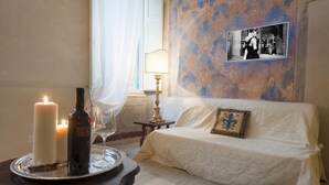 A cozy room with a bed, a table with candles and a bottle, a lamp, and a framed photo on the wall. - San Lorenzo Apartment (Firenze)