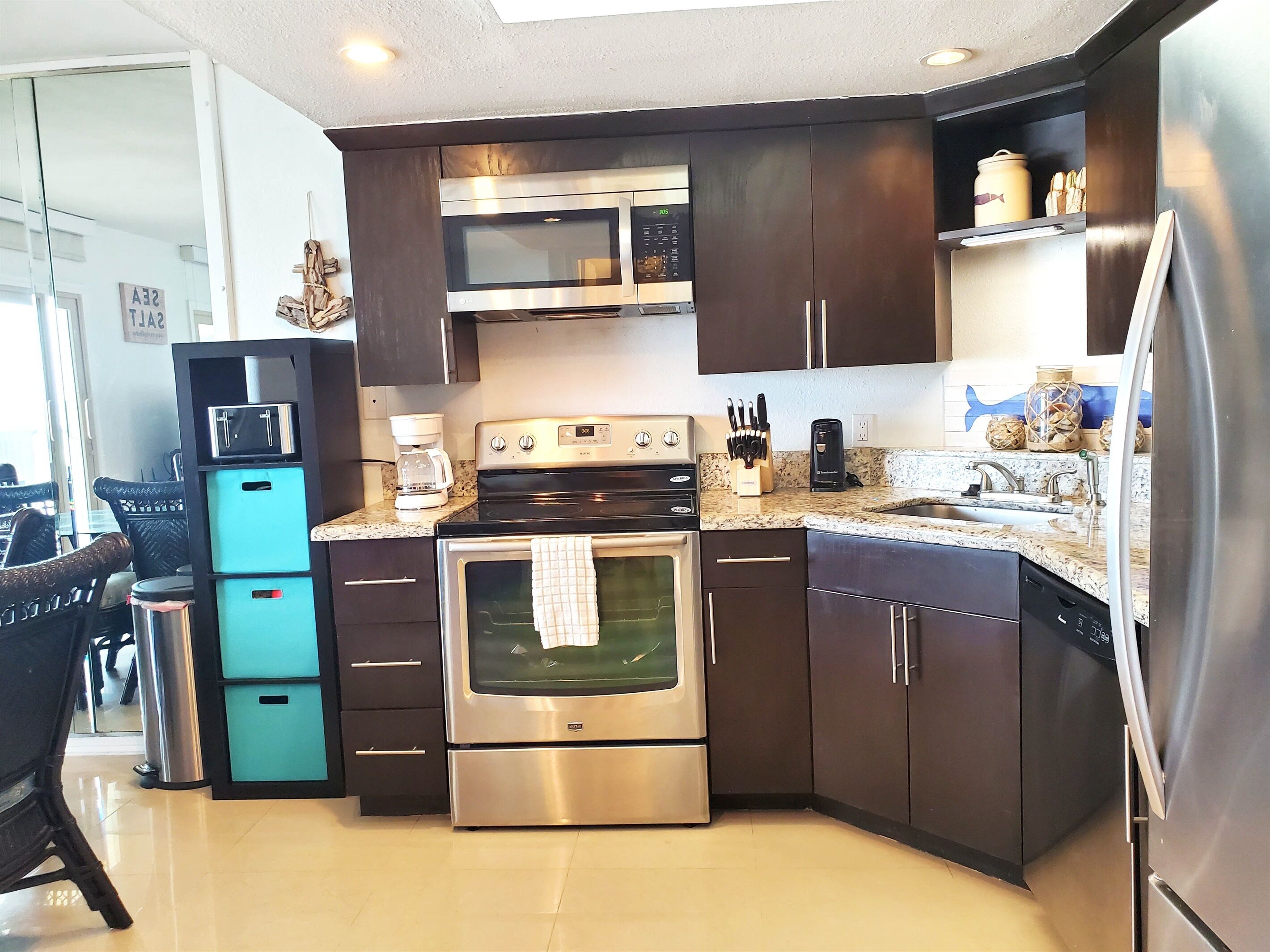 A modern kitchen with dark cabinets, stainless steel appliances, and a granite countertop.