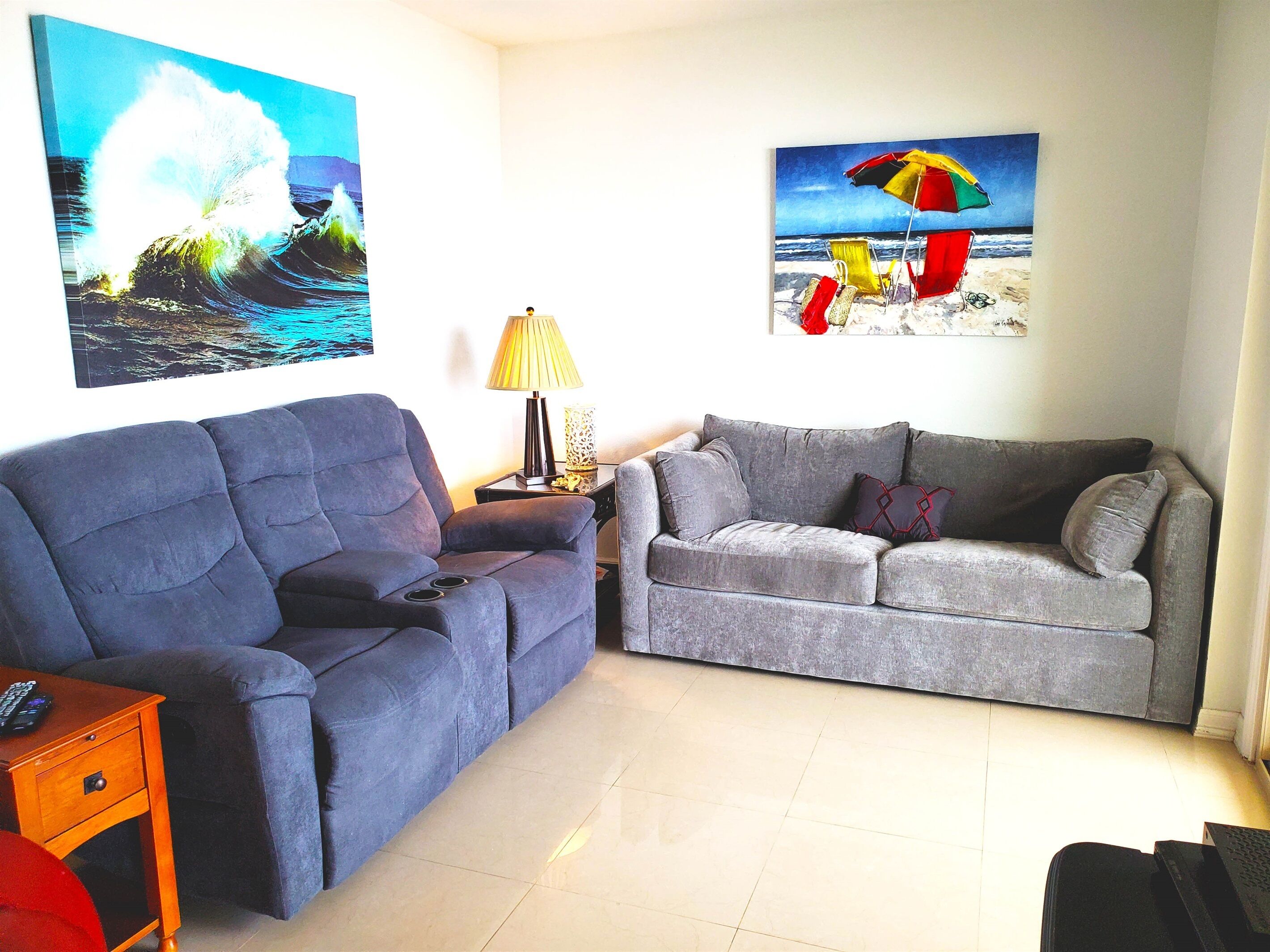 A living room with two sofas, a lamp, and two paintings on the wall.