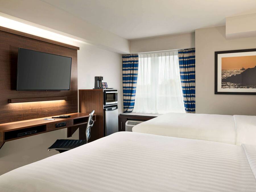 A hotel room with a bed, a desk with a flat-screen TV, a microwave, and a coffee maker.