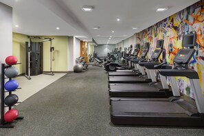 Un gimnasio con cintas de correr, pelotas de ejercicio y máquinas de pesas.