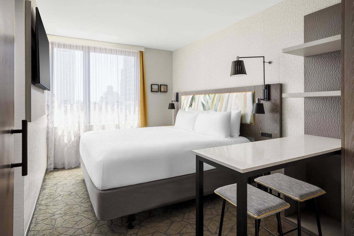 A hotel room with a bed, a desk, and a chair.