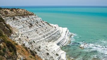 Una scogliera costiera con formazioni rocciose sedimentarie a strati.