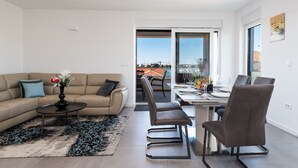 A modern living room with a sofa, coffee table, and dining area. - Apartment Birgir in Sukošan (Sukosan)