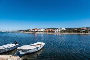 Two boats docked at a calm waterfront with buildings in the background. - Apartment Birgir in Sukošan (Sukosan)