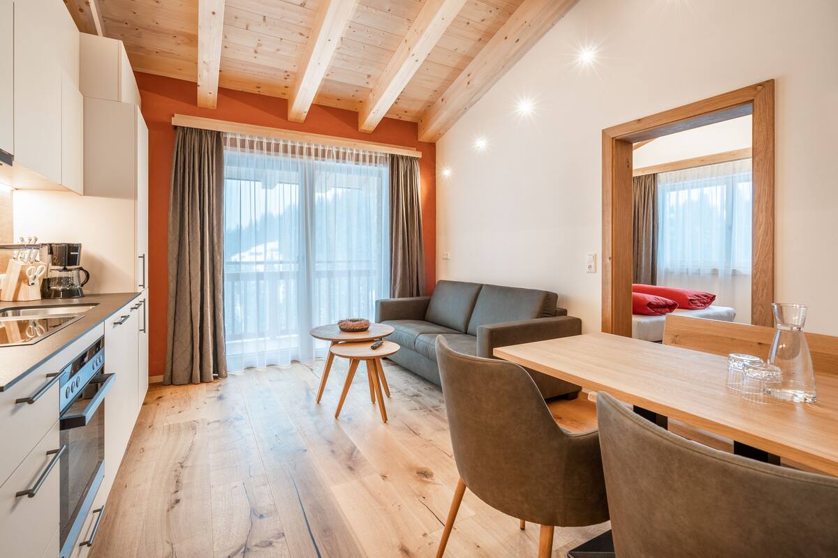 Una cocina moderna con comedor, suelo de madera y un sofá.