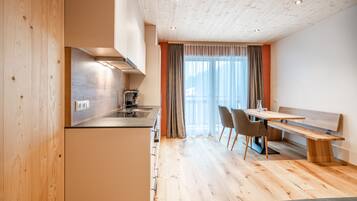 A modern kitchen with wooden cabinets, a built-in stove, and a dining area with a bench and chairs.