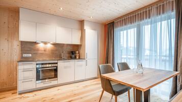 A modern kitchen with wooden cabinets, a built-in oven, and a dining area with a wooden table and chairs.