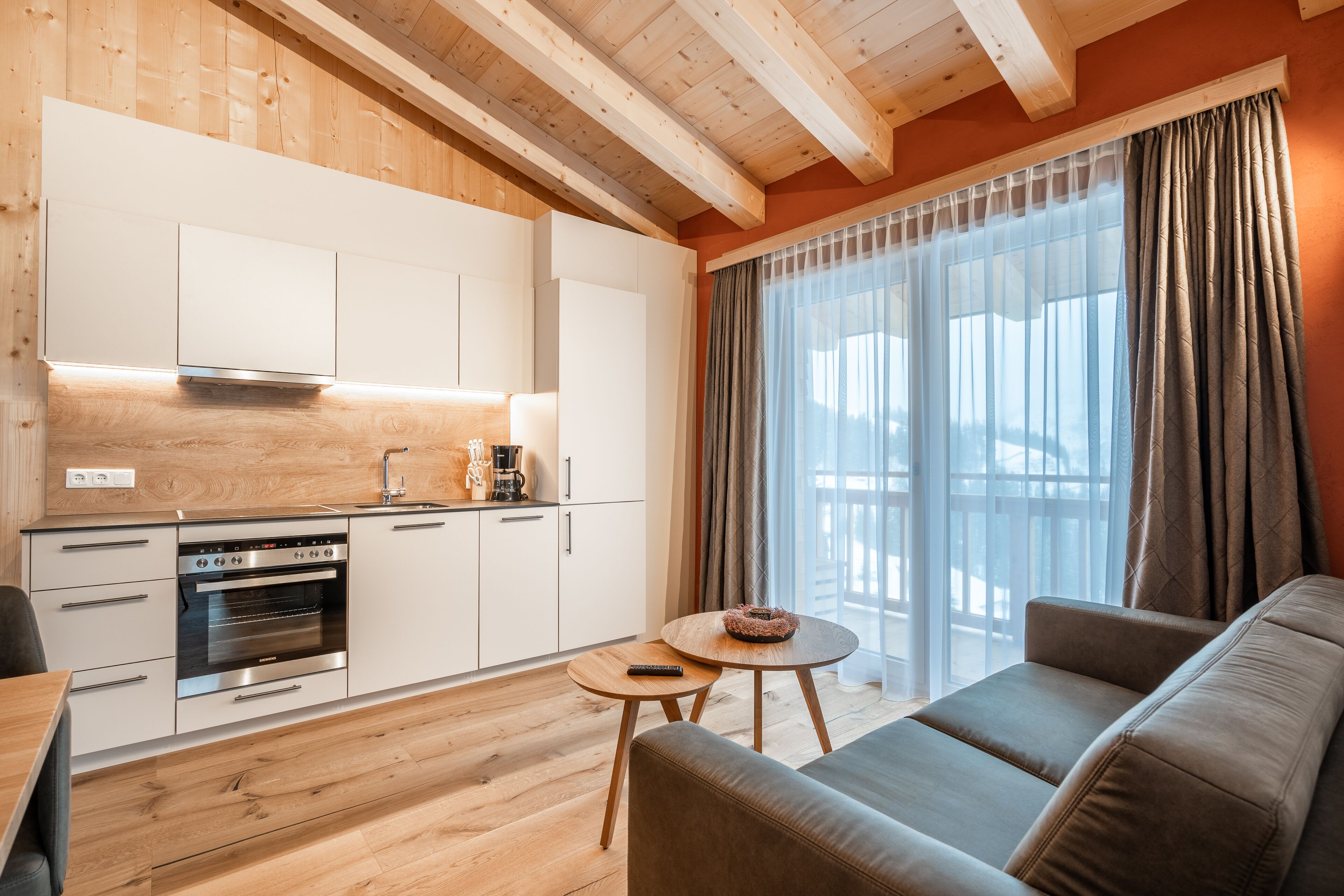 Una cocina moderna con armarios blancos, horno empotrado y una mesa de comedor de madera.