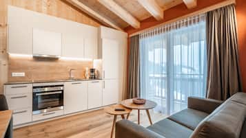 Una cocina moderna con armarios blancos, horno empotrado y una mesa de comedor de madera.