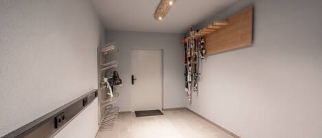 A hallway with a wooden ceiling, a door, and a rack of skis.