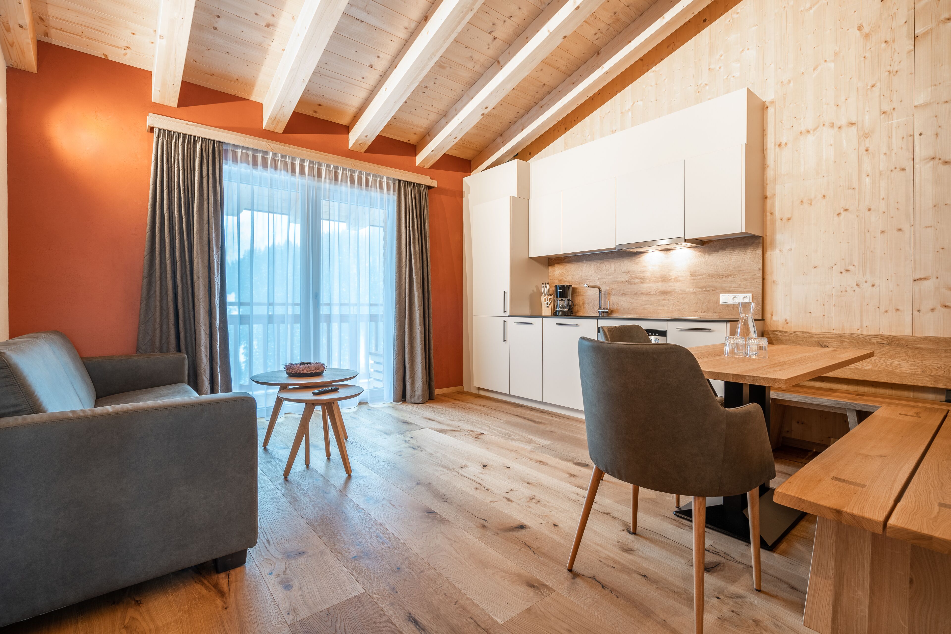 Un soggiorno moderno con un divano, un tavolo da pranzo e un angolo cottura con pensili in legno e un piano di lavoro.