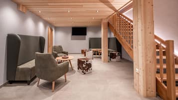 Un intérieur moderne avec un plafond en bois, des canapés gris, une petite table ronde et un escalier doté de rampes en bois.