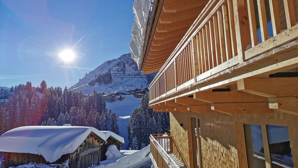 A wooden building with a balcony overlooking a snowy mountain landscape. - Naturhaus Gehren (Steeg)