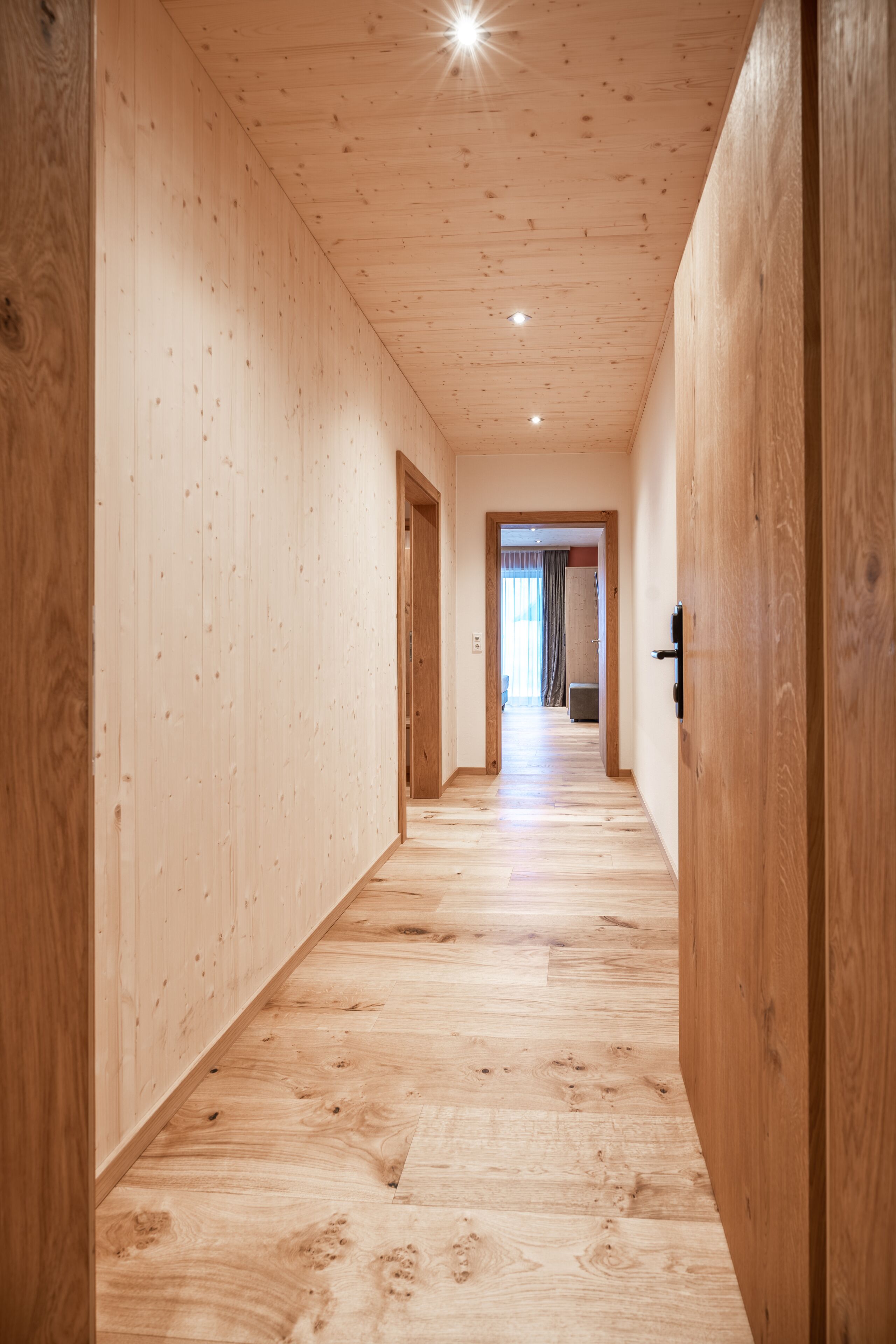 Un pasillo de madera con suelo y paredes de madera que conduce a una habitación con una puerta.