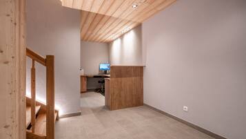 A spacious room with a wooden staircase, a desk, and a television in the background.