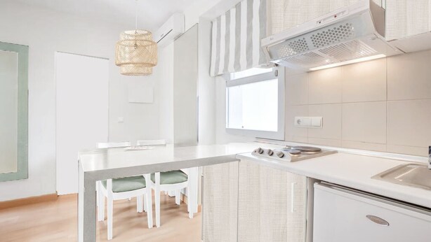 A modern kitchen with a white countertop, a built-in stove, and a small refrigerator. - Apartment with Pool View (Manacor)