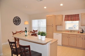 Kitchen features a central island with a dishwasher and a window with blinds.