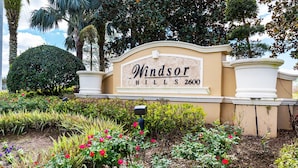 A sign for Windsor Hills with a landscaped garden in front. - Disney 6BR | Theater | Themed Bedrooms | Pool/Spa (Kissimmee)