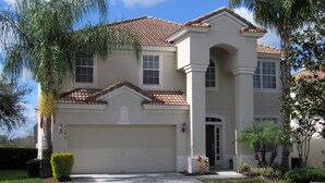 A two-story house with a tiled roof, a garage, and a front entrance. - Disney 6BR | Theater | Themed Bedrooms | Pool/Spa (Kissimmee)