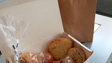 A box of assorted baked goods on a table with a brown paper bag in the background.
