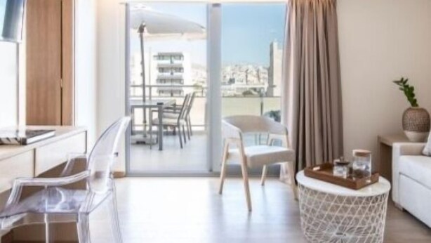 Una habitación de hotel moderna con balcón, zona de comedor y espacio de estar.