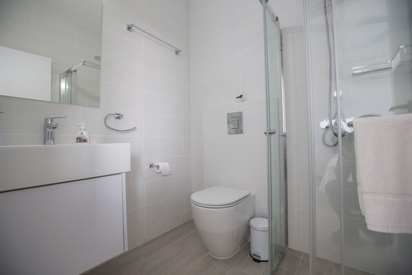 Un baño moderno con inodoro, lavabo y cabina de ducha de vidrio.
