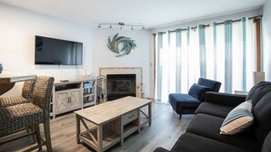 Un salon équipé d’un téléviseur, d’une cheminée, d’un canapé et d’un coin repas avec une table et des chaises.