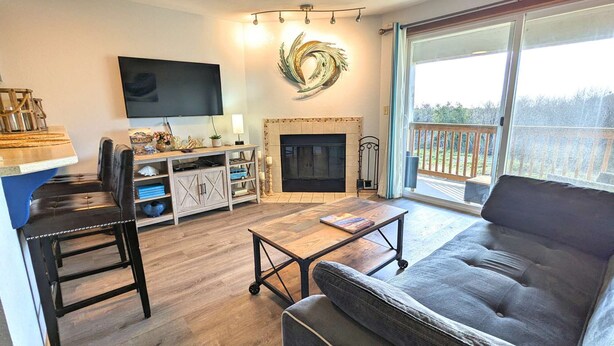 Un salon avec une cheminée, un téléviseur, un canapé et un balcon offrant une vue agréable.